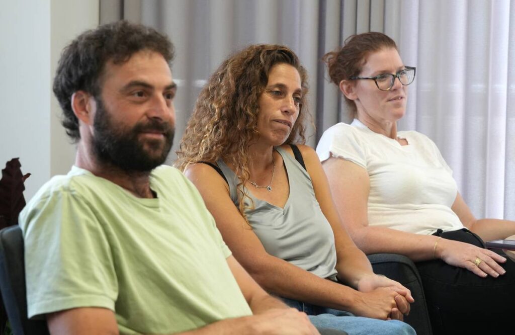 קבוצת אנשים יושבים יחד בחדר, מדברים ומקשיבים בריכוז.