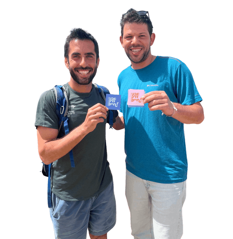 שני אנשים מחייכים מחזיקים כרטיסים צבעוניים עם כיתוב בעברית. אחד לובש חולצה תכלת והשני ירוקה.
